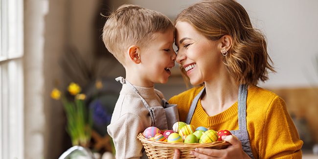 Mother holding son with basket full of Easter eggs