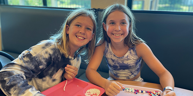 Two campers smile with their bead crafts.