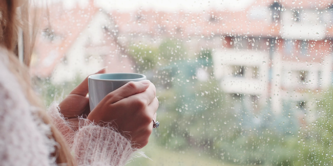 Woman looking out window holding a cup of coffee