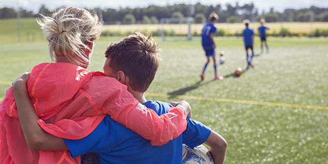 Mother And Son Embracing In Soccer Field