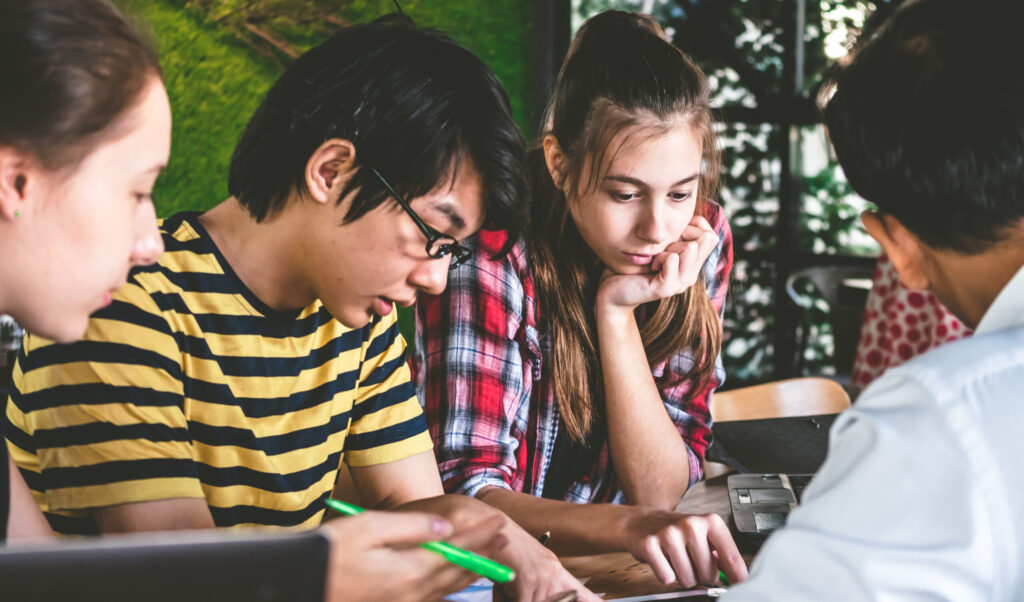 Multi Ethnic Group Of Students Working On Task Together. Teamwor