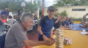 A young man plays a game with an elderly man on a Youthfront Missional Journey