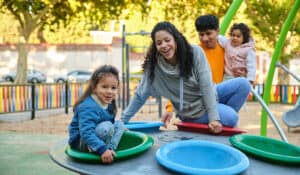 Latin family with two children playing together on a playground.